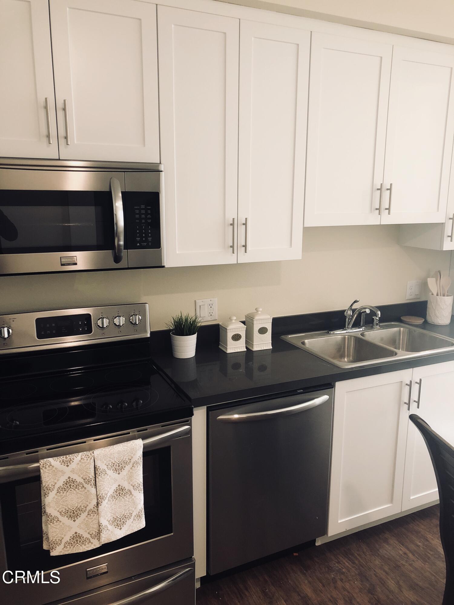 300 West 9th Street Oxnard, CA 93030 - Photo 12 of 12 a kitchen with stainless steel appliances granite countertop a stove a microwave and white cabinets