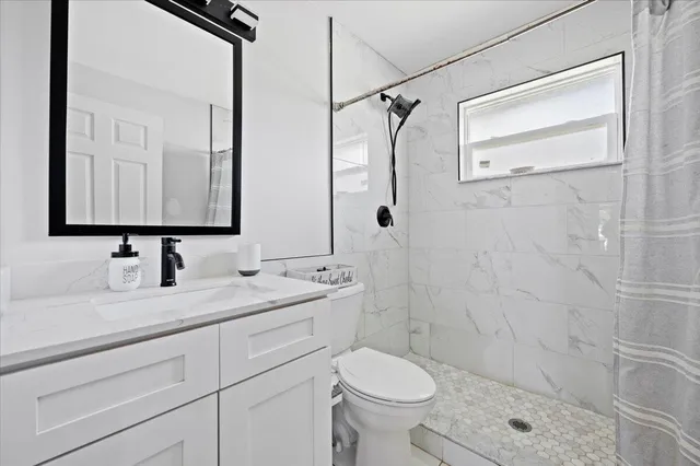 a bathroom with a granite countertop sink toilet and shower