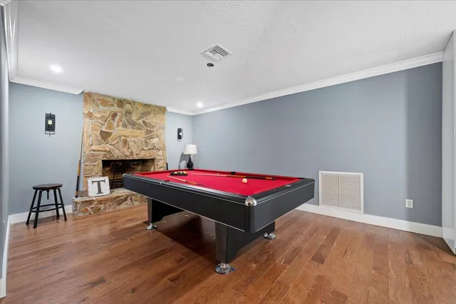 a room with pool table and a wooden floor