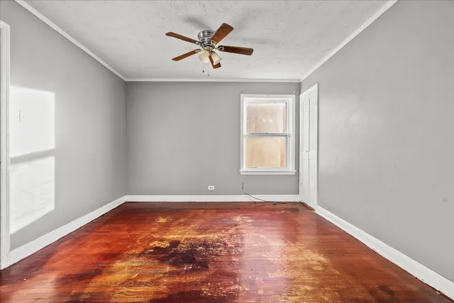 a view of empty room with wooden floor and fan