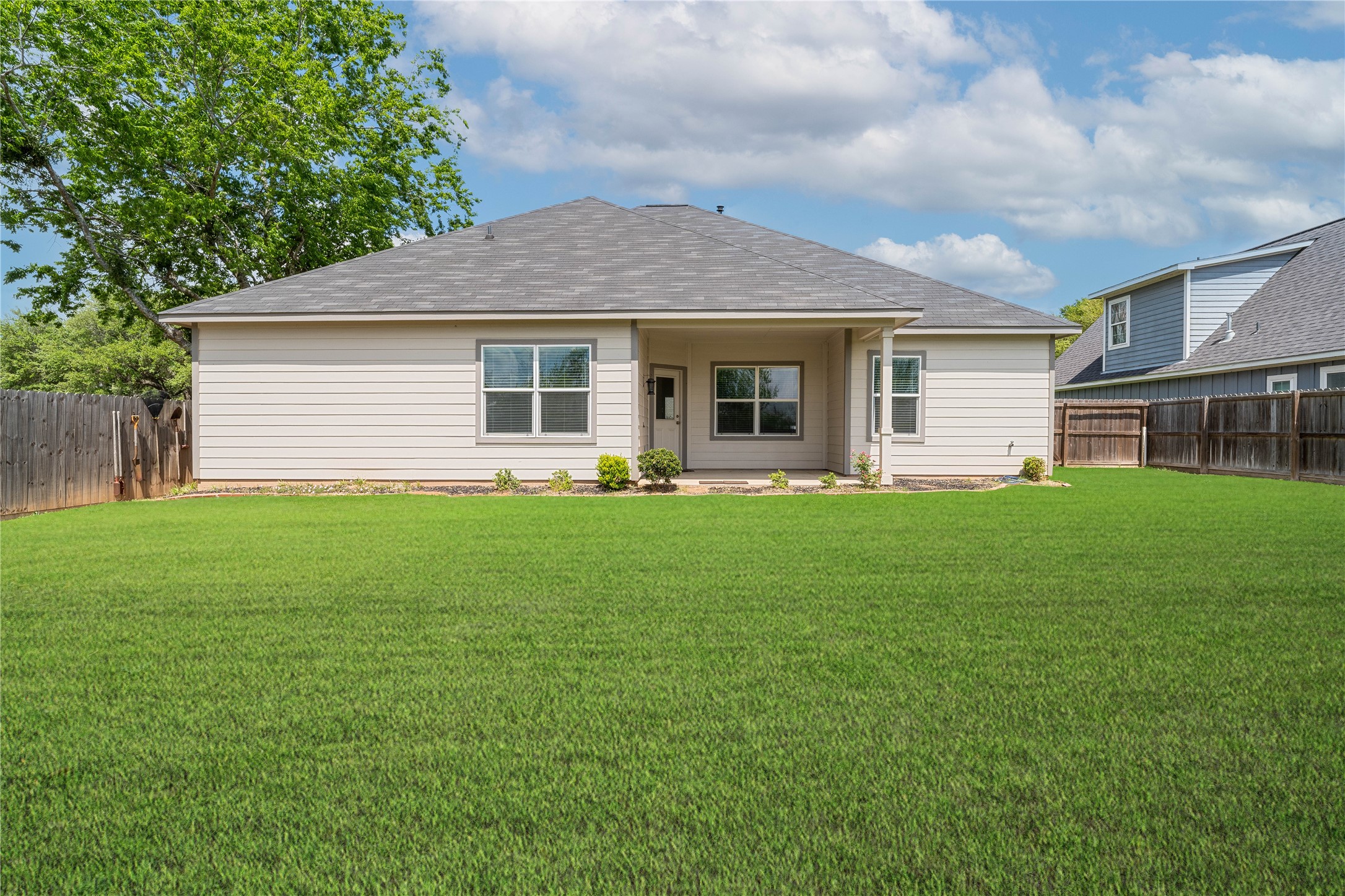 231 McCormick Street Columbus, TX 78934 - Photo 26 of 27 Backyard – Rear view of the home showcasing a covered patio and generous yard space, ideal for relaxing or entertaining outdoors.