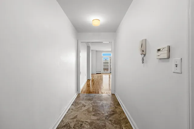 a view of a hallway with wooden floor and a bathroom
