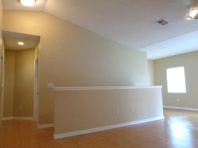 an empty room with wooden floor and windows with curtains