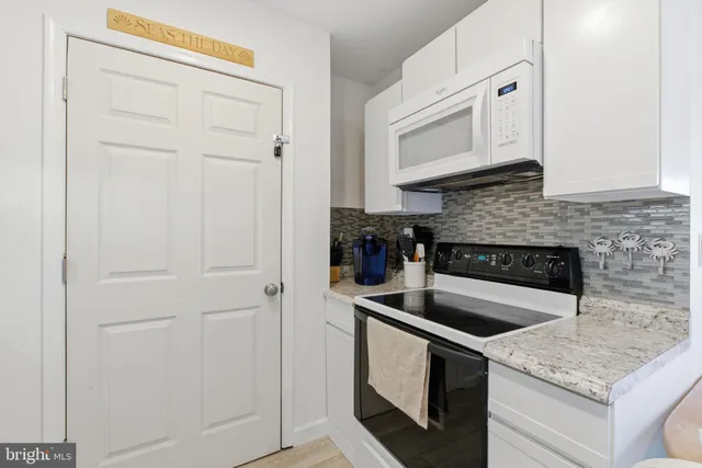 a kitchen with granite countertop white cabinets and black appliances