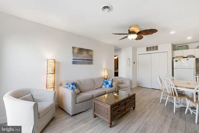 a living room with furniture a wooden floor and a ceiling fan