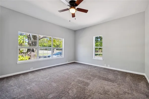 an empty room with windows and ceiling fan