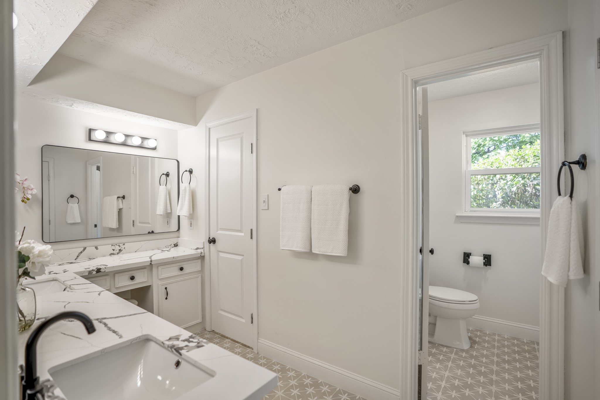 6303 Larkmount Drive Spring, TX 77389 - Photo 23 of 50 Moving into the primary ensuite, the updated vanity stretches across two walls and meets in the corner, giving the space plenty of counter space, storage, and room to spread out. Framed mirrors, quartz counters, and modern fixtures add a fresh feel, while the closed door near the far sink leads into one of two walk-in closets.