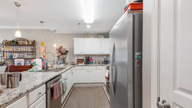 a kitchen with stainless steel appliances granite countertop a refrigerator a sink dishwasher a stove and a dining table with wooden floor