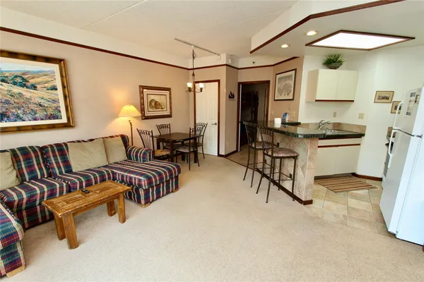 a living room with furniture and a dining table with wooden floor