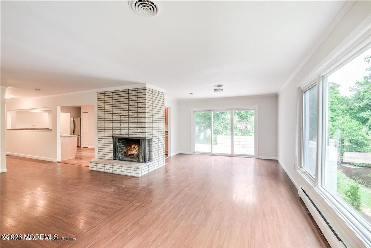 699 Aldrich Road Howell, NJ 07731 - Photo 3 of 23 an empty room with wooden floor fireplace and windows