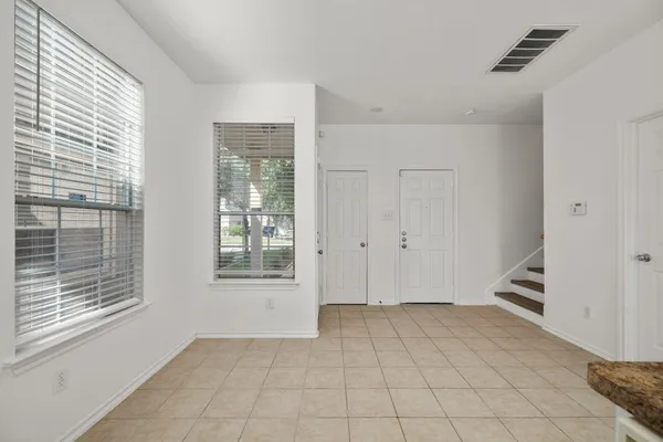 a view of an empty room with window and hardwood floor