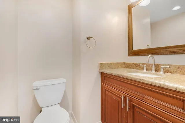 a bathroom with a granite countertop toilet sink and mirror
