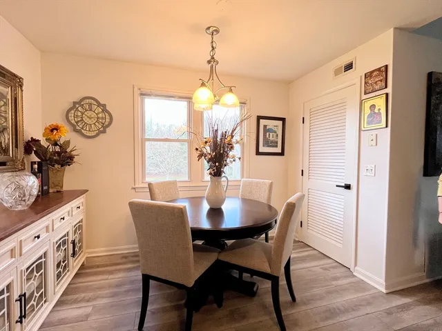 a dining room with chandelier and wooden floor