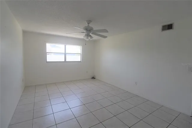 an empty room with windows and fan