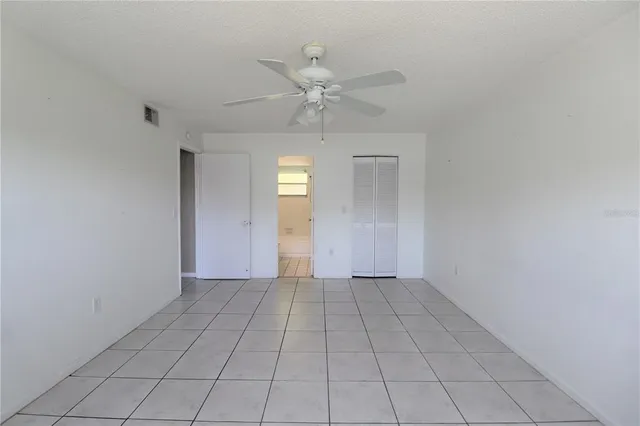 a view of an empty room with window and chandelier fan