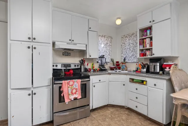 a kitchen that has cabinets a sink and chairs in it