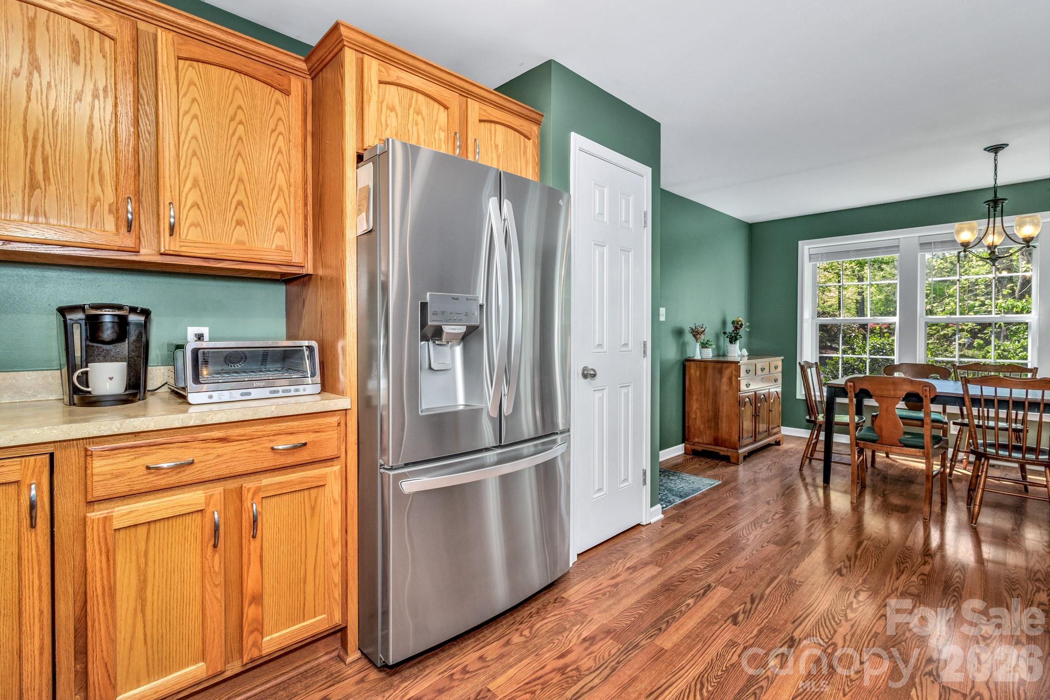 152 Joe Jenkins Road Fairview, NC 28730 - Photo 13 of 44 a kitchen with stainless steel appliances granite countertop a refrigerator a stove a dining table and chairs with wooden floor
