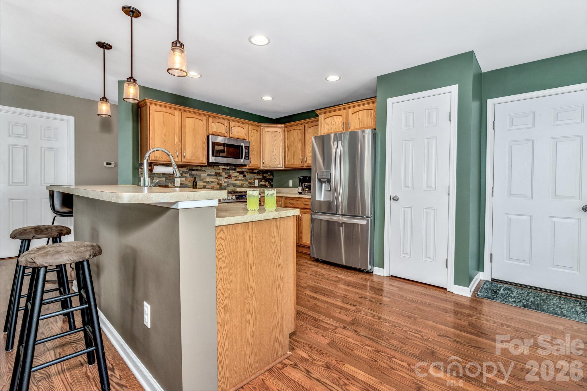 152 Joe Jenkins Road Fairview, NC 28730 - Photo 15 of 44 a kitchen with stainless steel appliances granite countertop a refrigerator a sink dishwasher a stove top oven a dining table and chairs with wooden floor