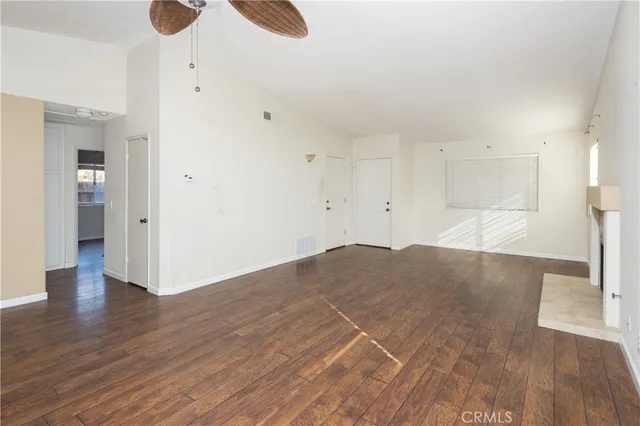 a view of an empty room with wooden floor fireplace and a window