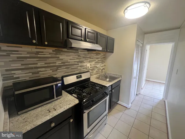 a kitchen with granite countertop cabinets stove top oven and microwave