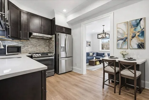 a kitchen with stainless steel appliances a dining table chairs stove and refrigerator