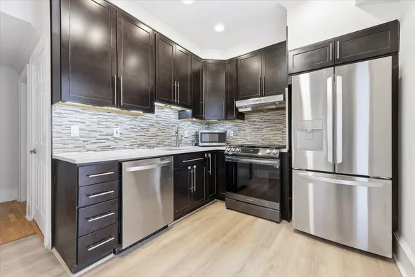 a kitchen with stainless steel appliances kitchen island granite countertop a refrigerator and a stove top oven
