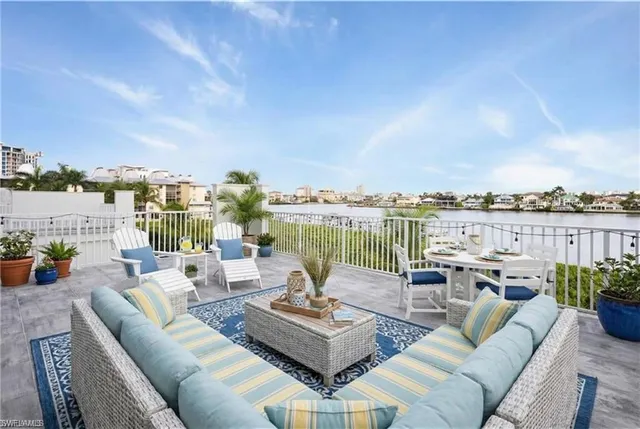 a view of a patio with couches potted plants and ocean view