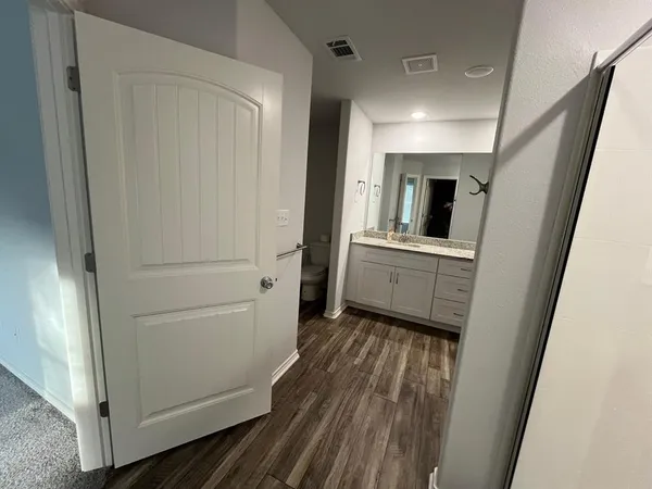 a view of a hallway with wooden floor and cabinets
