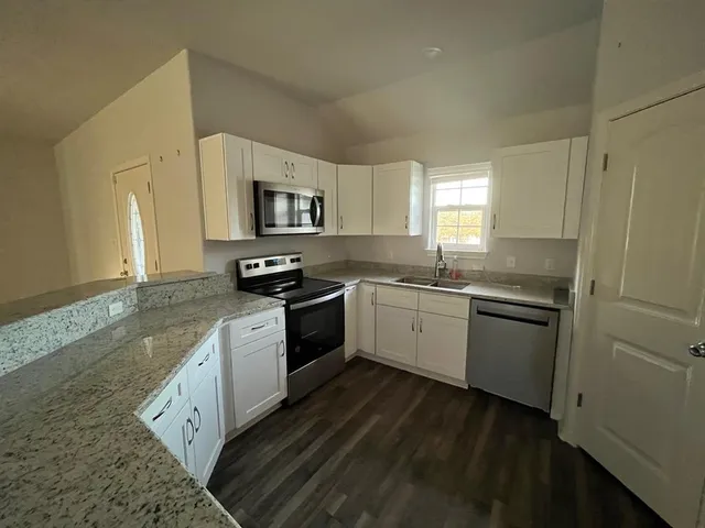 a kitchen with granite countertop white cabinets and stainless steel appliances