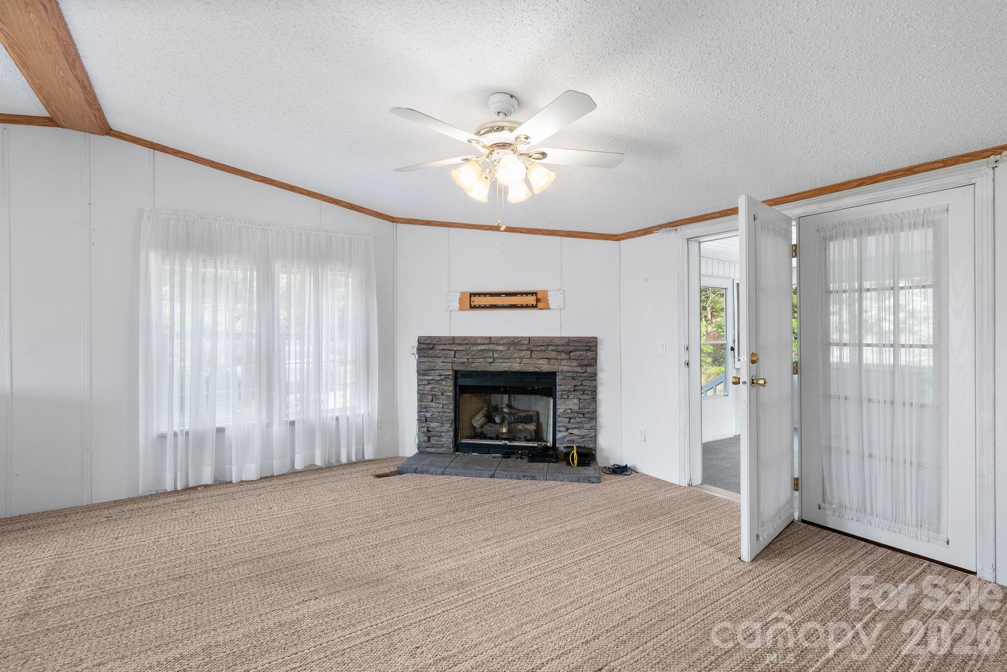 133 Spivey Mountain Road Asheville, NC 28806 - Photo 4 of 40 an empty room with fireplace fan and windows
