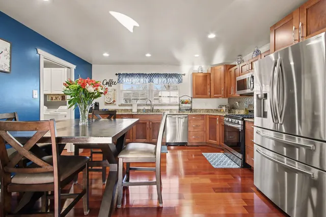 a kitchen with granite countertop stainless steel appliances a sink counter space and a dining table