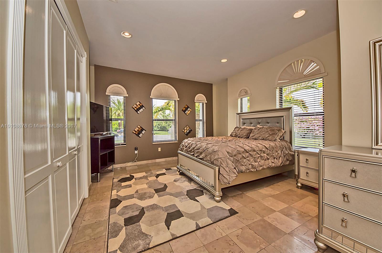 10270 Southwest 58th Street Miami, FL 33173 - Photo 24 of 35 a bedroom with a large bed and a chandelier