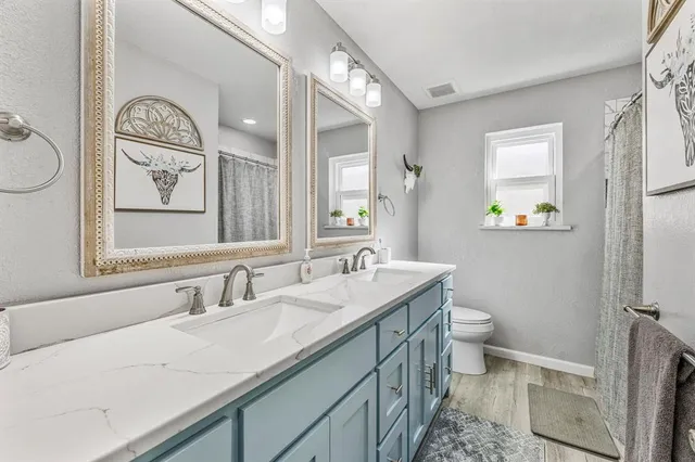 a bathroom with a granite countertop sink mirror and toilet