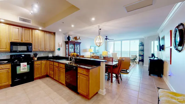a kitchen with stainless steel appliances granite countertop wooden cabinets a sink a stove a dining table and chairs