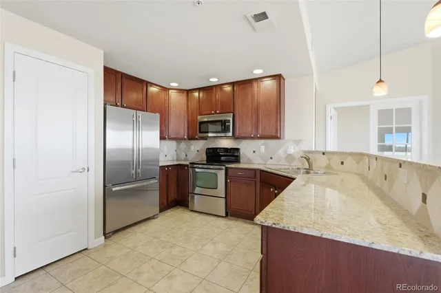 a kitchen with stainless steel appliances granite countertop a refrigerator and a stove top oven
