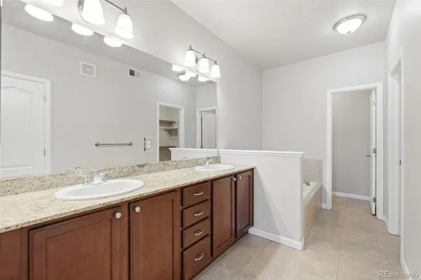 a bathroom with a granite countertop double vanity sink and a mirror