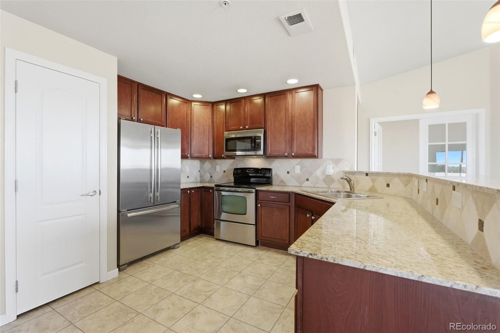 6223 Kilmer Loop, Unit 201 Golden, CO 80403 - Photo 10 of 44 a kitchen with granite countertop a refrigerator a sink a stove top oven and cabinetry