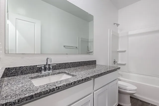 a bathroom with a granite countertop sink a toilet and a mirror