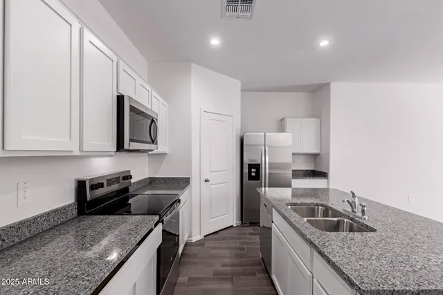 a kitchen with granite countertop a sink a counter top space stainless steel appliances and cabinets