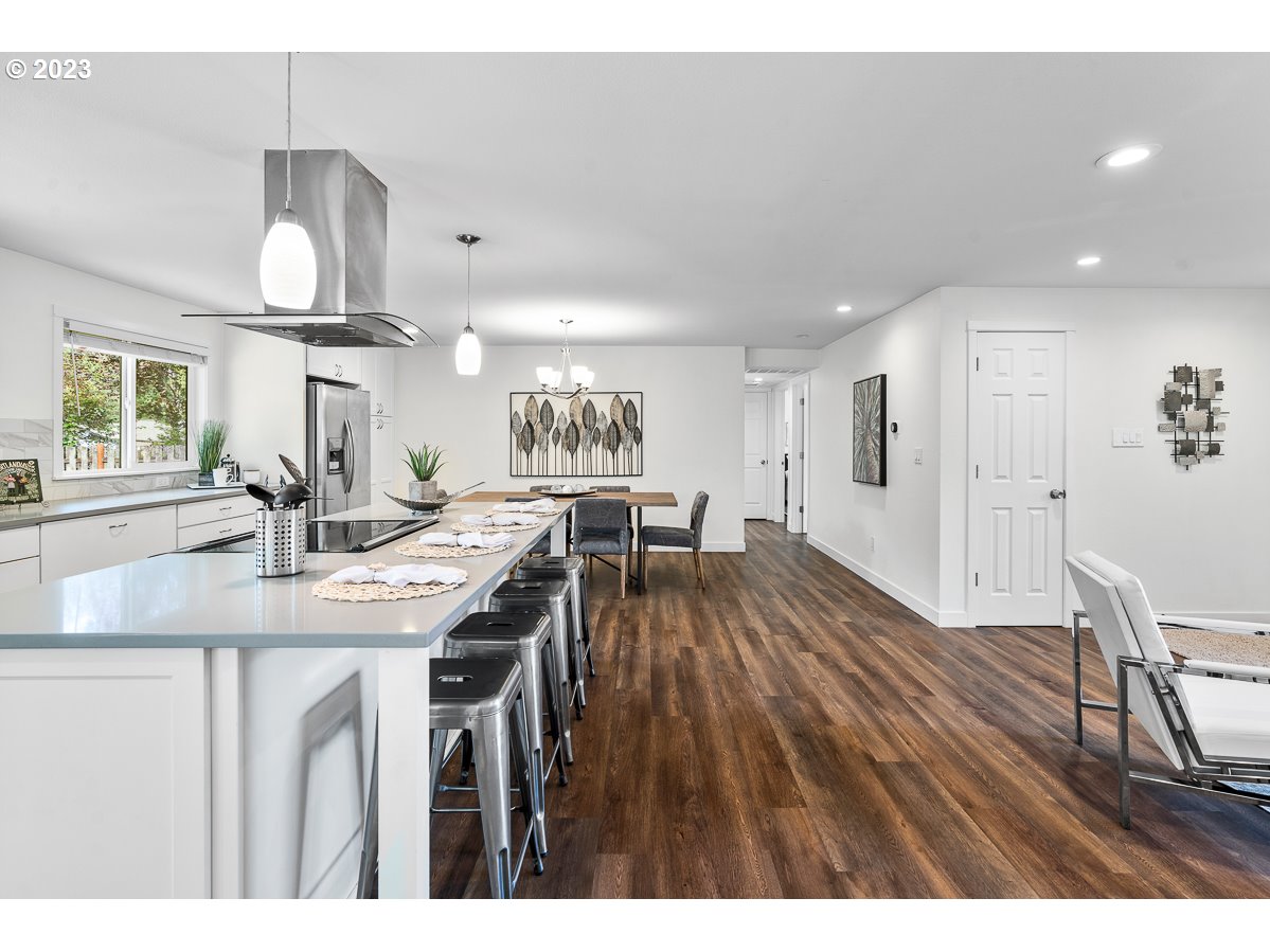 14720 Southwest Glenbrook Road Beaverton, OR 97007 - Photo 11 of 43 a kitchen with stainless steel appliances granite countertop a refrigerator a sink dishwasher a dining table and chairs with wooden floor