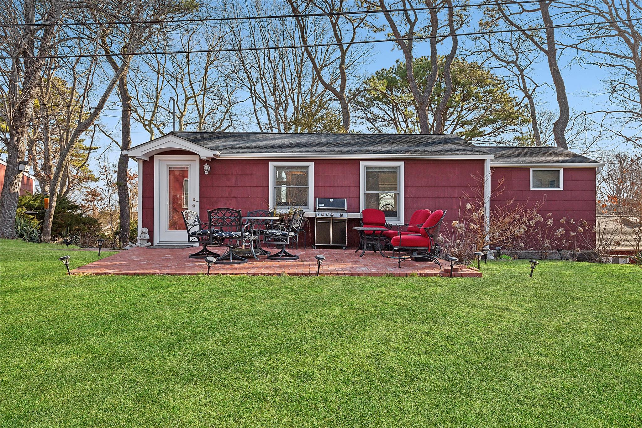 Rear view of house featuring a yard, roof with shingles, and a patio
