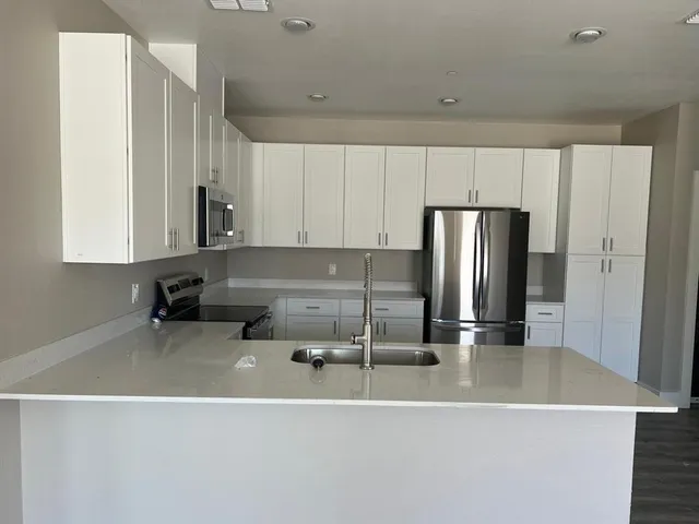 a kitchen with a refrigerator a stove and white cabinets