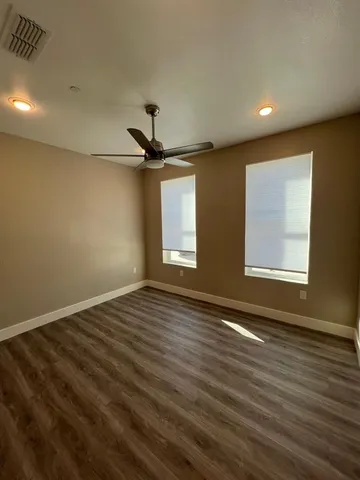 a view of empty room with wooden floor and fan