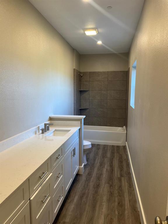 443 Richlands Way Fate, TX 75087 - Photo 6 of 20 Bathroom with dark wood finished floors, vanity, a textured wall, and shower / tub combination