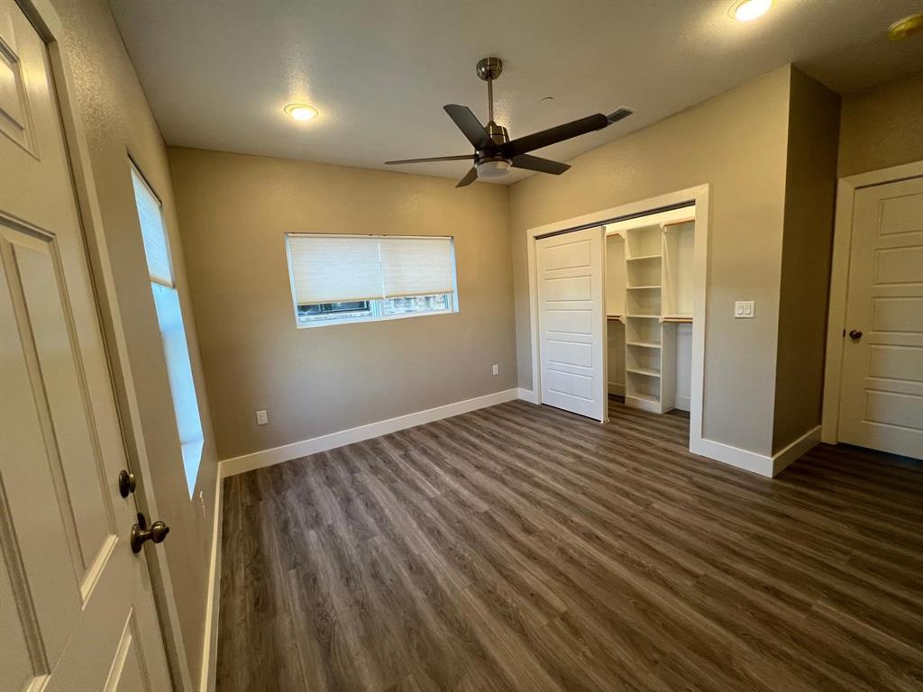 443 Richlands Way Fate, TX 75087 - Photo 8 of 20 Unfurnished bedroom with a barn door, dark wood finished floors, a closet, a ceiling fan, and recessed lighting