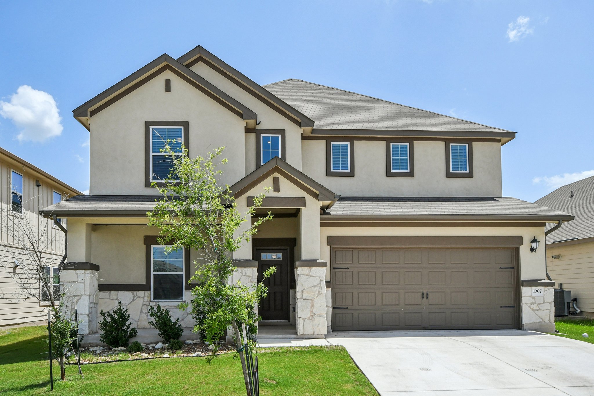 Traditional-style house featuring stucco siding, concrete driveway, stone siding, and an attached garage