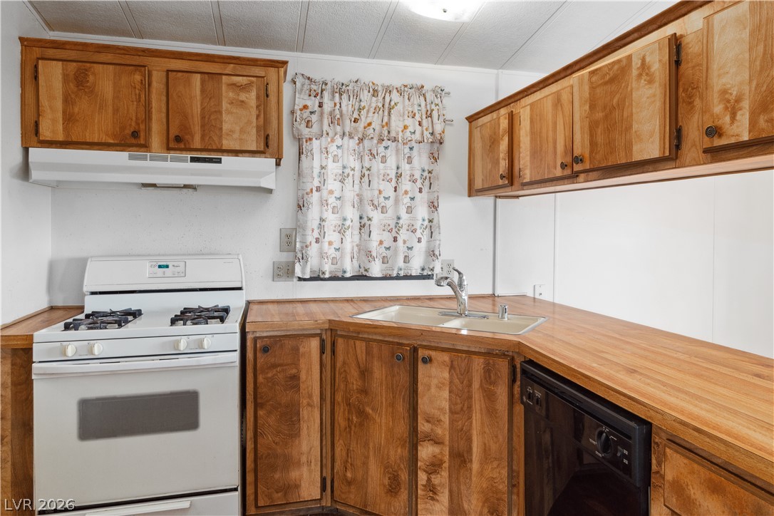 1671 Granada Street Laughlin, NV 89029 - Photo 12 of 63 Kitchen with black dishwasher, white gas range oven, brown cabinetry, under cabinet range hood, and a sink