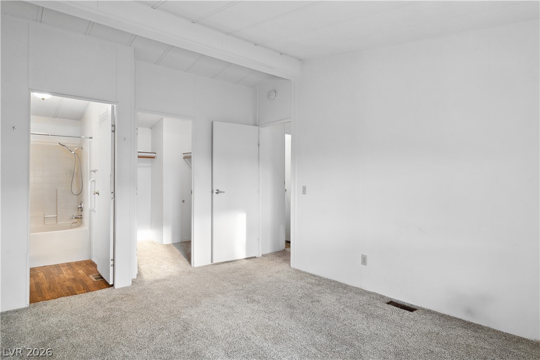 1671 Granada Street Laughlin, NV 89029 - Photo 22 of 63 Primary bedroom featuring carpet floors, vaulted ceiling with beams, visible vents, a spacious closet, and ensuite bath