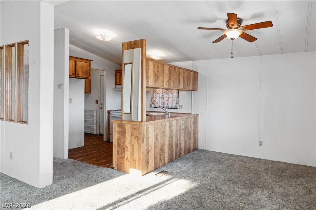 1671 Granada Street Laughlin, NV 89029 - Photo 10 of 63 Dining area with breakfast bar/passthrough window to Kitchen with wood cabinetry, lofted ceiling, dark carpet, and gas stove