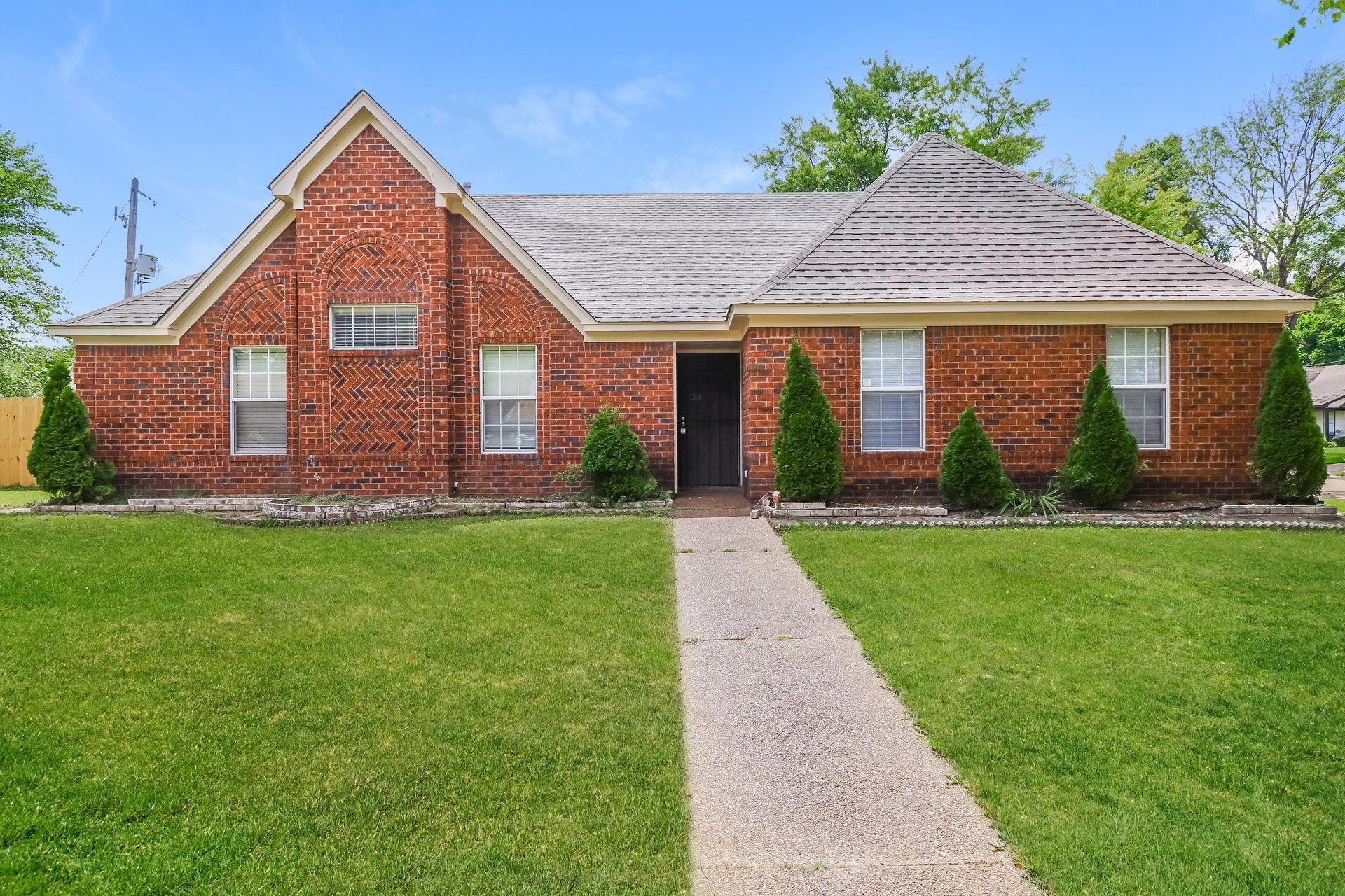 View of front of property with a front lawn, brick siding, and a shingled roof